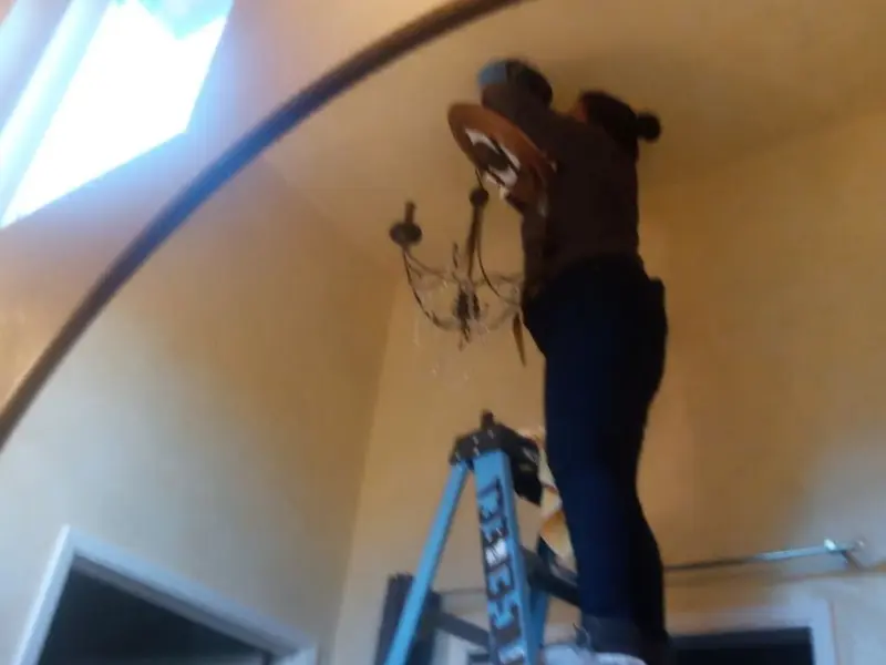 Electrician installing a chandelier in a Hot Springs Village residence